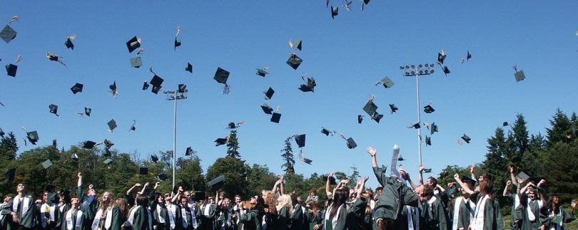Studiumsabsolventen schmeißen ihre Doktorhüte in die Luft