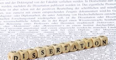 Eine Reihe aus Buchstaben gelegt mit Würfeln, die das Wort Dissertation bildet - Doktortitel