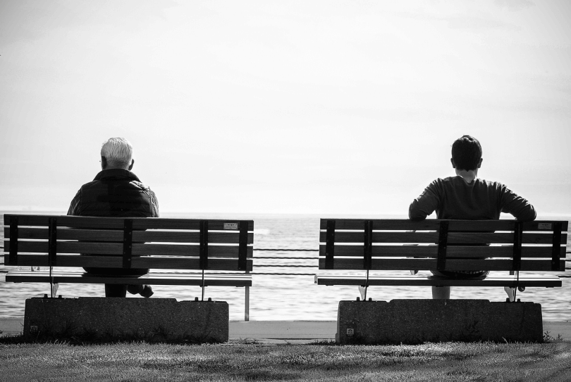 junger und alter Mann sitzen auf zwei Bänken