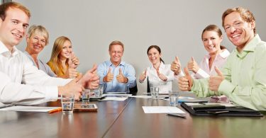 Geschäftsleute halten Daumen hoch im Business Meeting