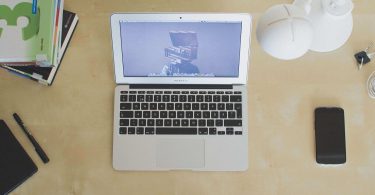 Laptop, Lehrbücher, Stifte, Notizbuch auf Schreibtisch