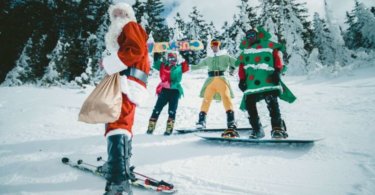Ausgefallene Weihnachtsfeier Vier Skifahrer in weihnachtlichen Kostüm